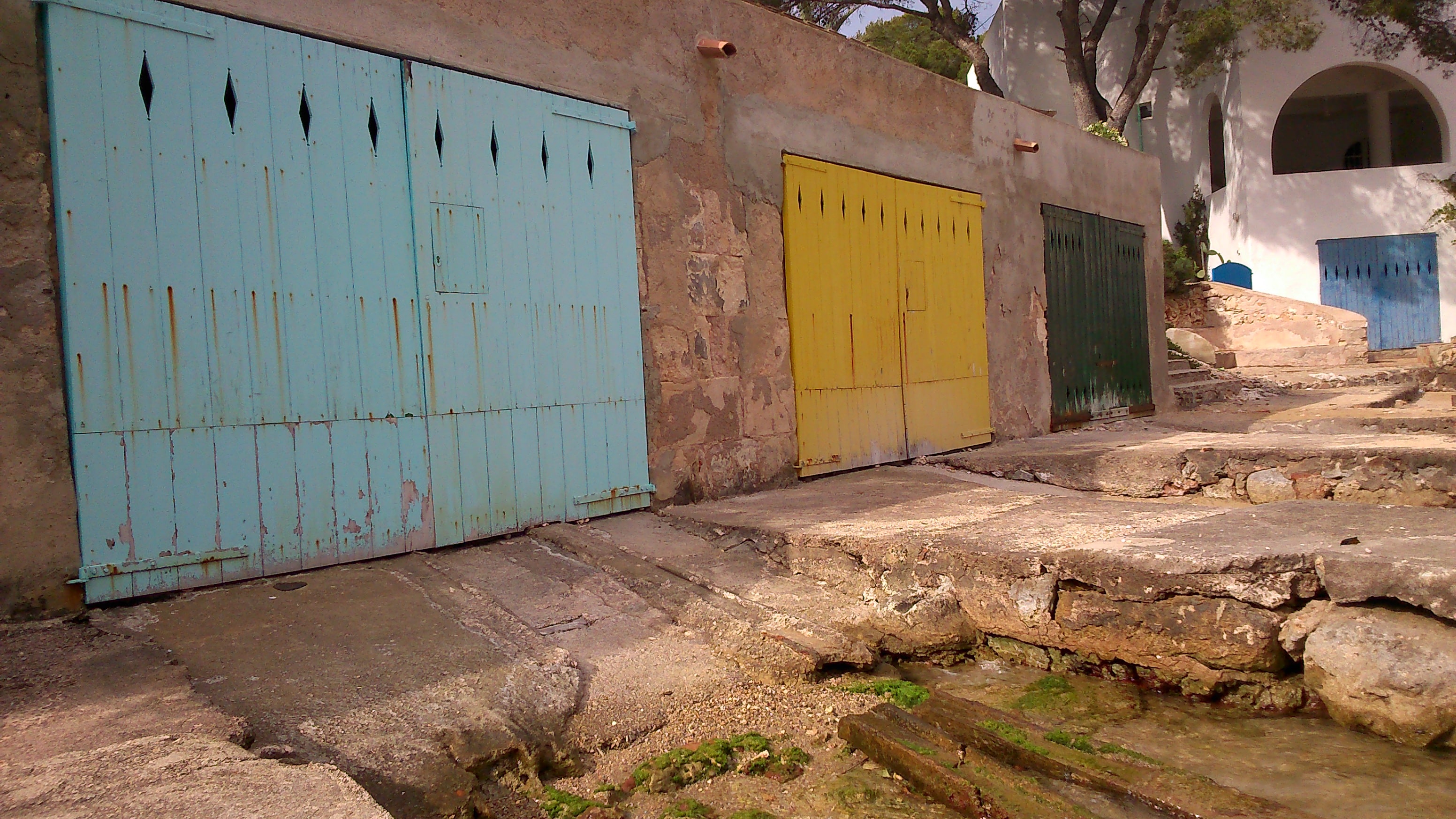 Blue, yellow and green doors beside stone slipways in Cala d’Or