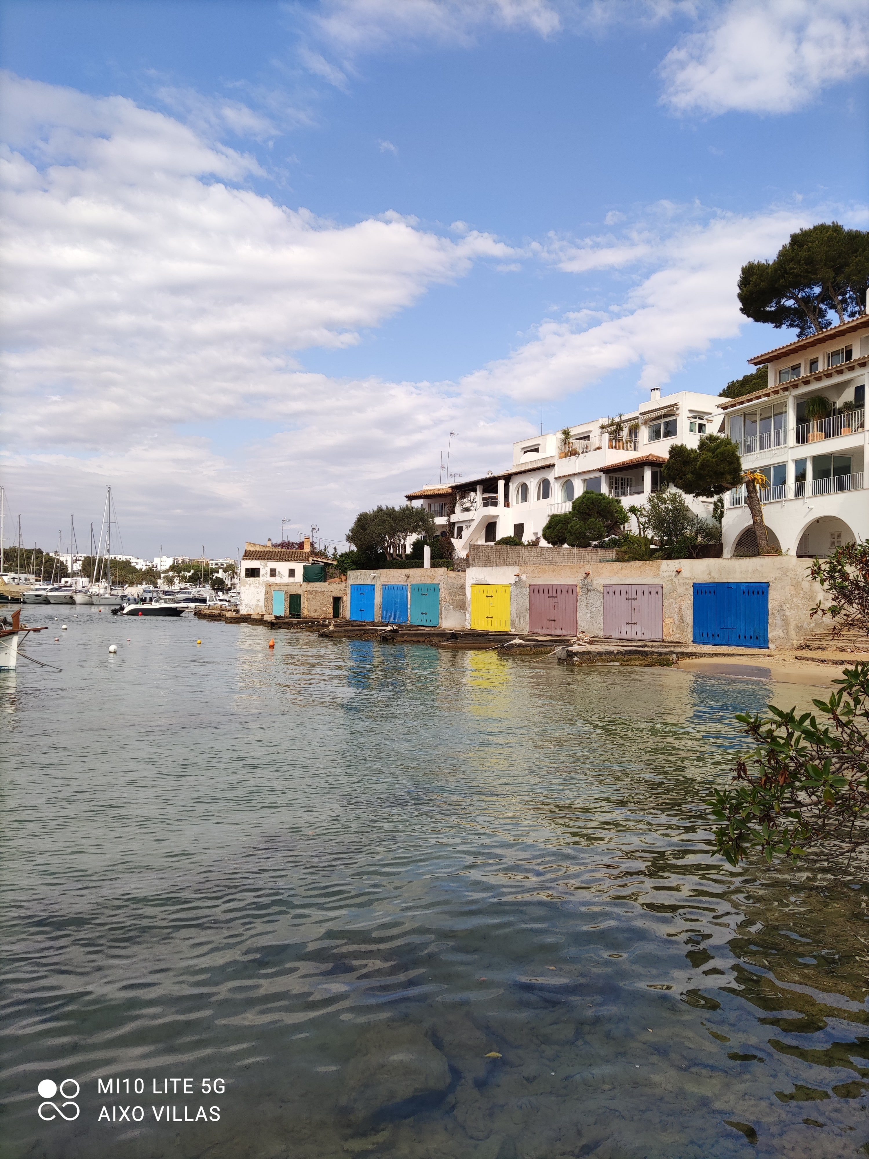 Cala d’Or harbour with boats, white houses and colourful doors beside the water